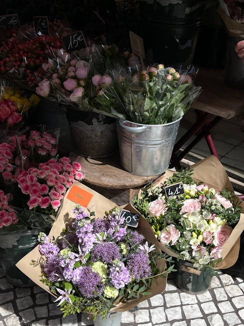A display of fresh floral bouquets arranged for flower delivery, featuring a variety of flowers including pale pink roses, lavender, and purple blossoms, all arranged in brown paper wrapping with blac